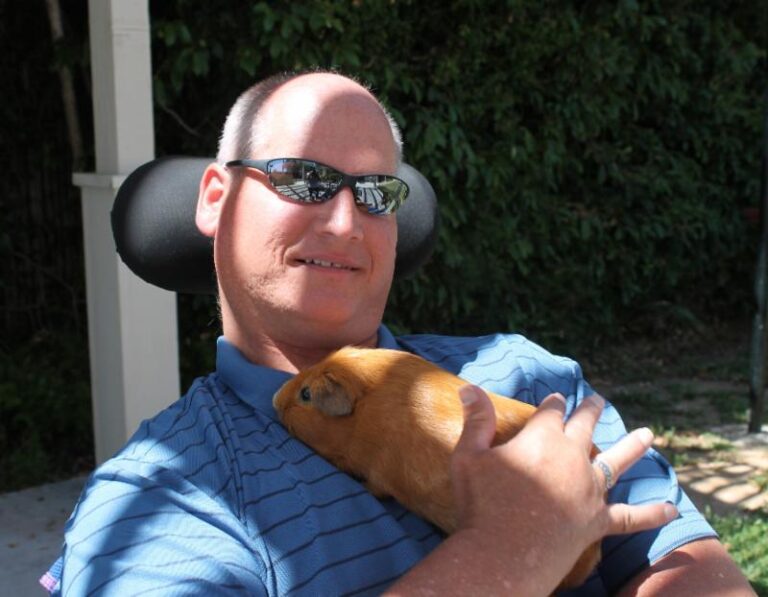 A man wearing spectacles holding his pet